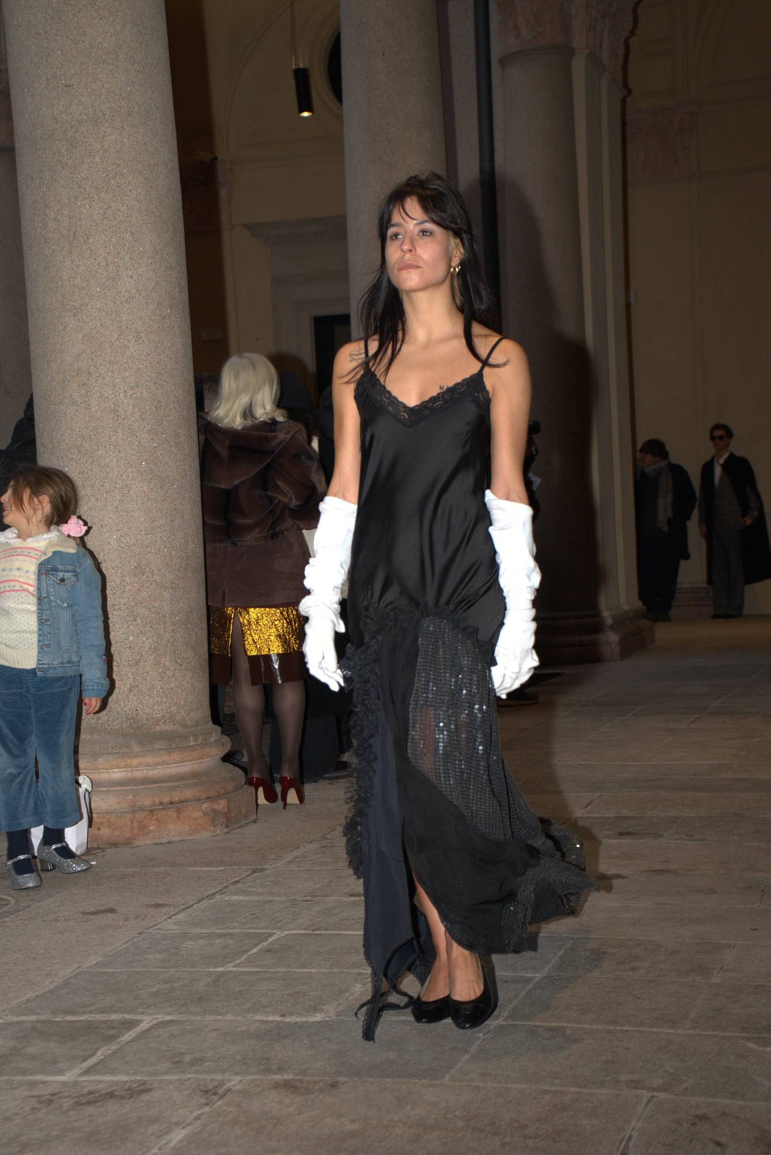 Designed by Lessico Familiare, a delicate slip dress layered with sequins and lace, paired with sculptural gloves. Intimacy and evening ritual meet everyday reuse in a quiet silhouette.