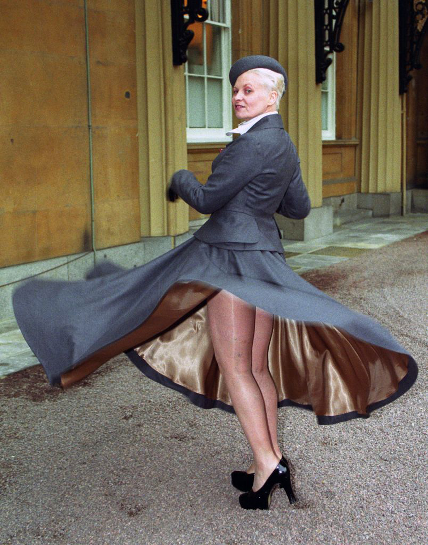 Vivienne Westwood at Buckingham Palace, London, where she received her OBE from Queen Elizabeth II. While giving a twirl for the photographers, she showed that beneath her tailored suit she was not wearing knickers